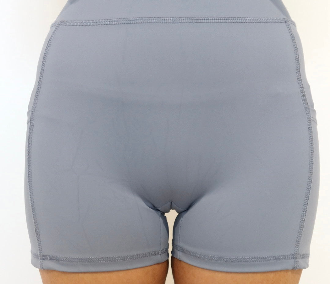 Grey athletic shorts without a cameltoe concealer on a plain background